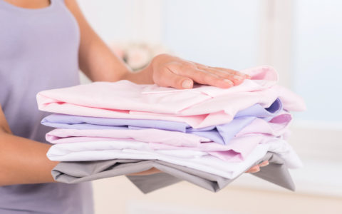 Stack of colorful clothes. Portrait of woman holding stack of clothes